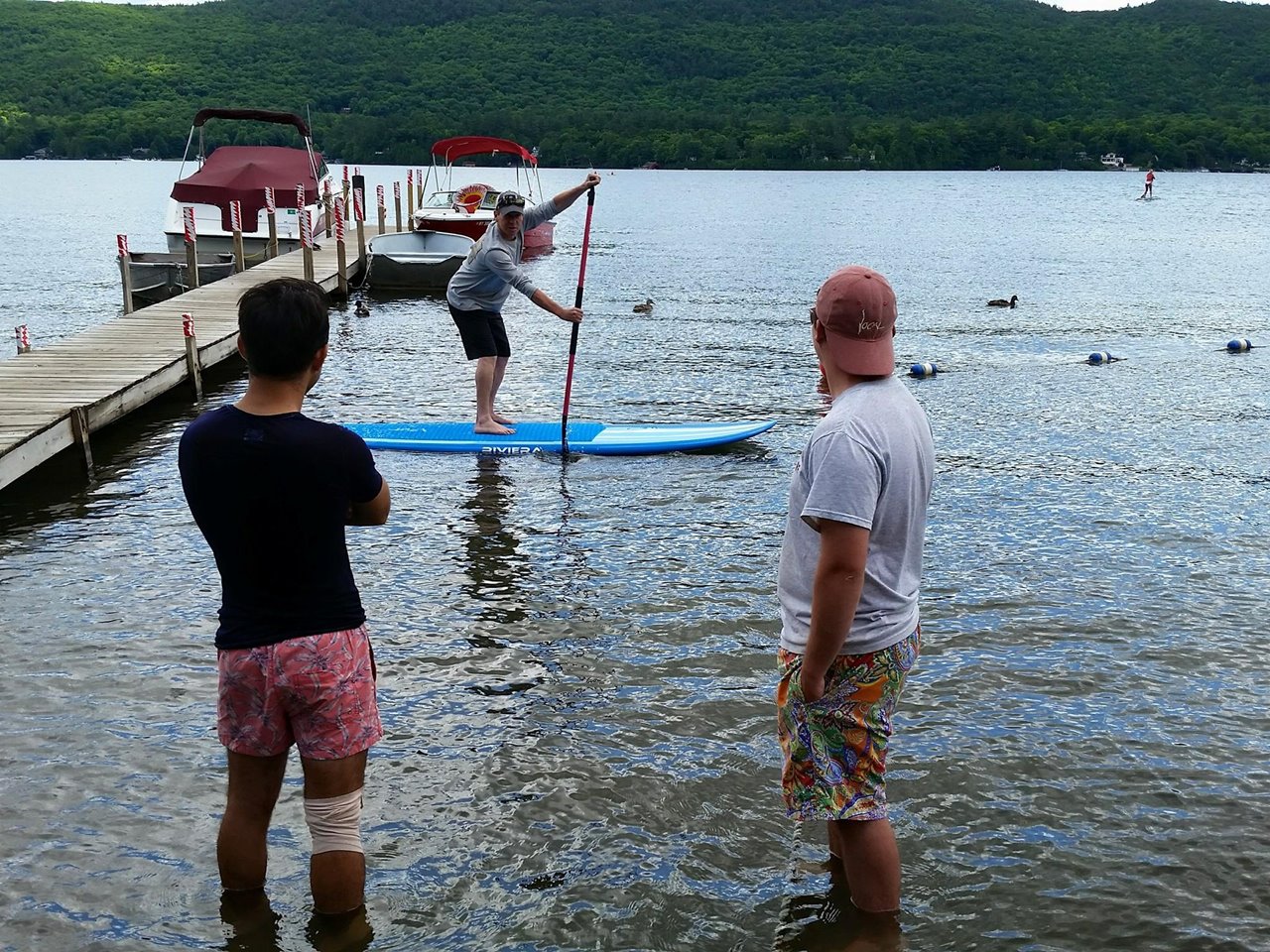 Two men watching person on stand up paddleboard.