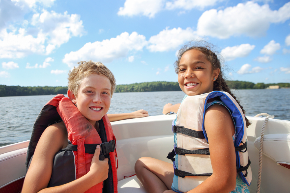 Kids with lifejackets on a boat enjoying Lake George water sports